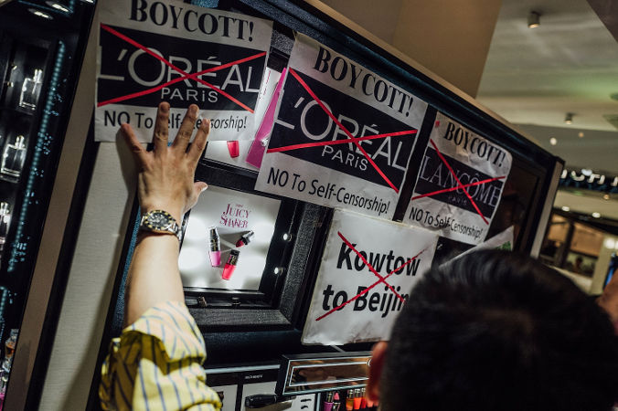  Demonstranci naklejają plakaty podczas protestu przeciwko francuskiej firmie kosmetycznej Lancôme przed jej sklepem na Causeway Bay w Hongkongu, 8 czerwca 2016 r. (Anthony Kwan / Getty Images)